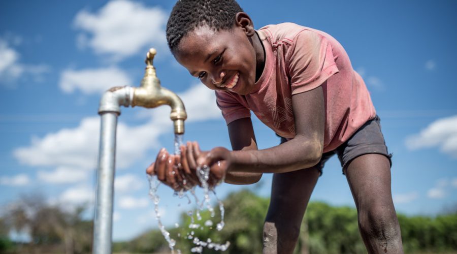 Purity* (10yrs) drinks water from a tap connected to an Oxfam solar piped water system in Bubi District, Zimbabwe.